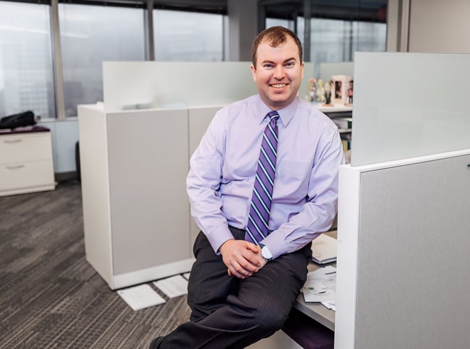 Meaden & Moore advisor Carlin smiling and sitting at desk
