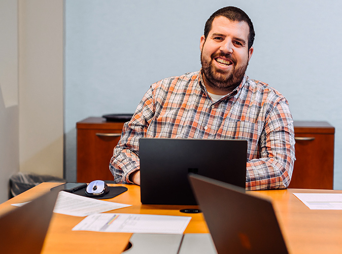 Meaden & Moore employee smiling sitting at table with computer