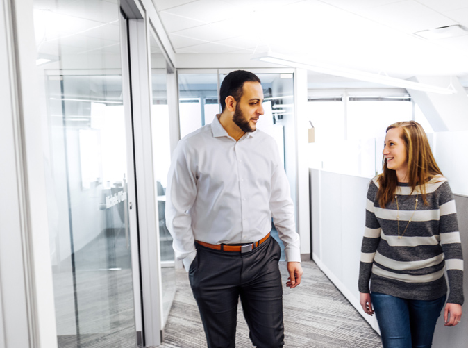 man and woman talking and walking through office