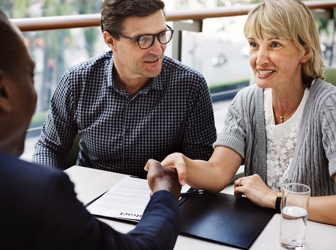 woman and man shaking hands in agreement during business meeting