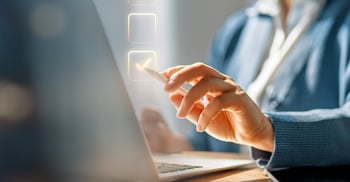 A person wearing a business suit and pointing at a laptop screen