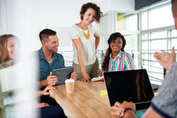 Multi ethnic group of succesful creative business people using a laptop during candid meeting-1