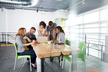 Multi ethnic group of succesful creative business people using a laptop during candid meeting-2