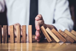 Businessman stopping domino effect on table