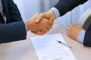 Two People Shaking Hands After Signing a Contract