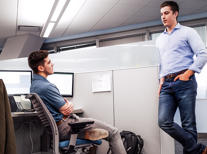 two men talking at a cubicle