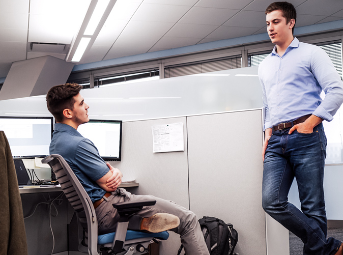 two young professionals talking at cubicle