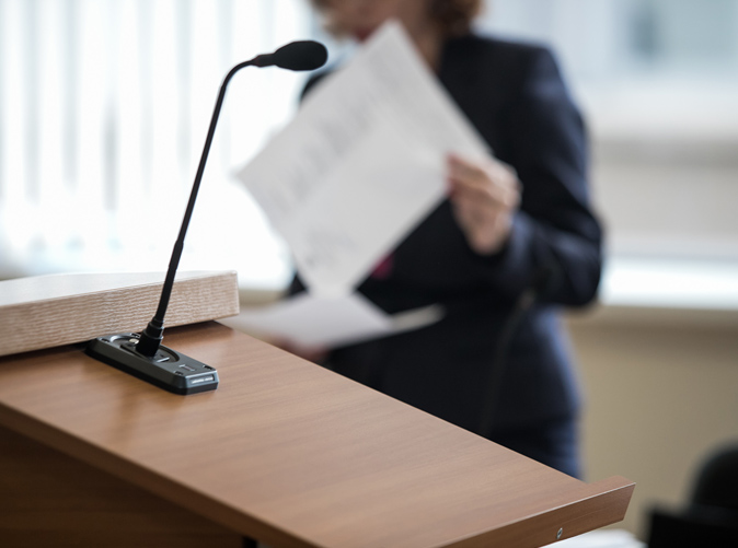woman standing behind podium holding paper