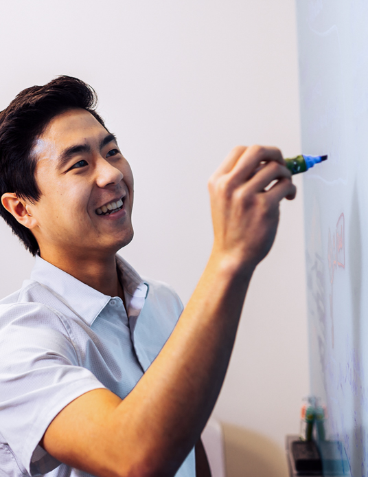 man writing on whiteboard with marker