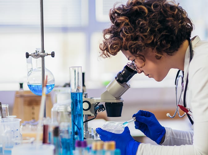 researcher looking into microscope in a lab