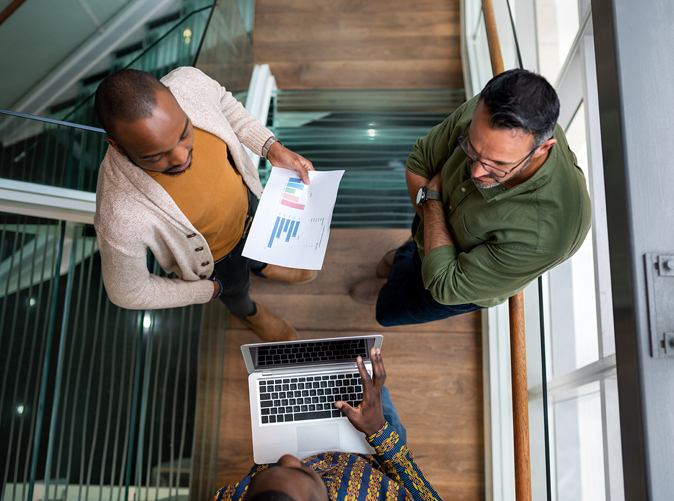 three men discussing data in office setting