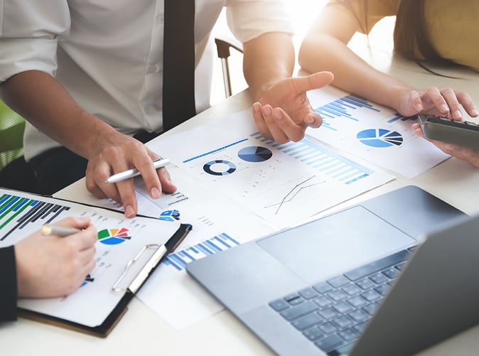 laptop and paperwork with charts and data