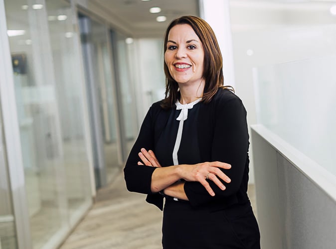 professional woman standing in office smiling with arms folded
